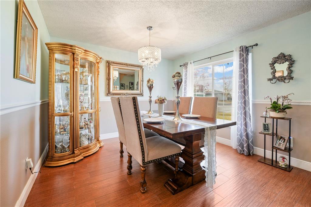 A dining room features a wooden table, upholstered chairs, a curio cabinet, and hardwood floors — 709 CLIFTON HILLS STREET, ORLANDO, FL