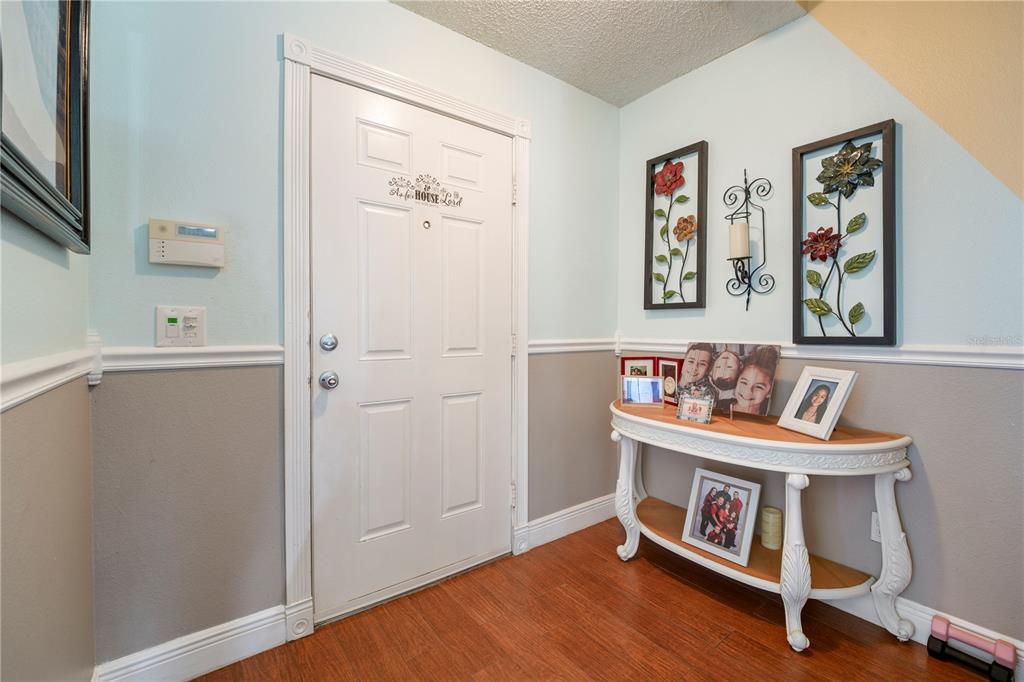 An entryway features a white door, wood flooring, a console table, and wall-mounted floral decor — 709 CLIFTON HILLS STREET, ORLANDO, FL