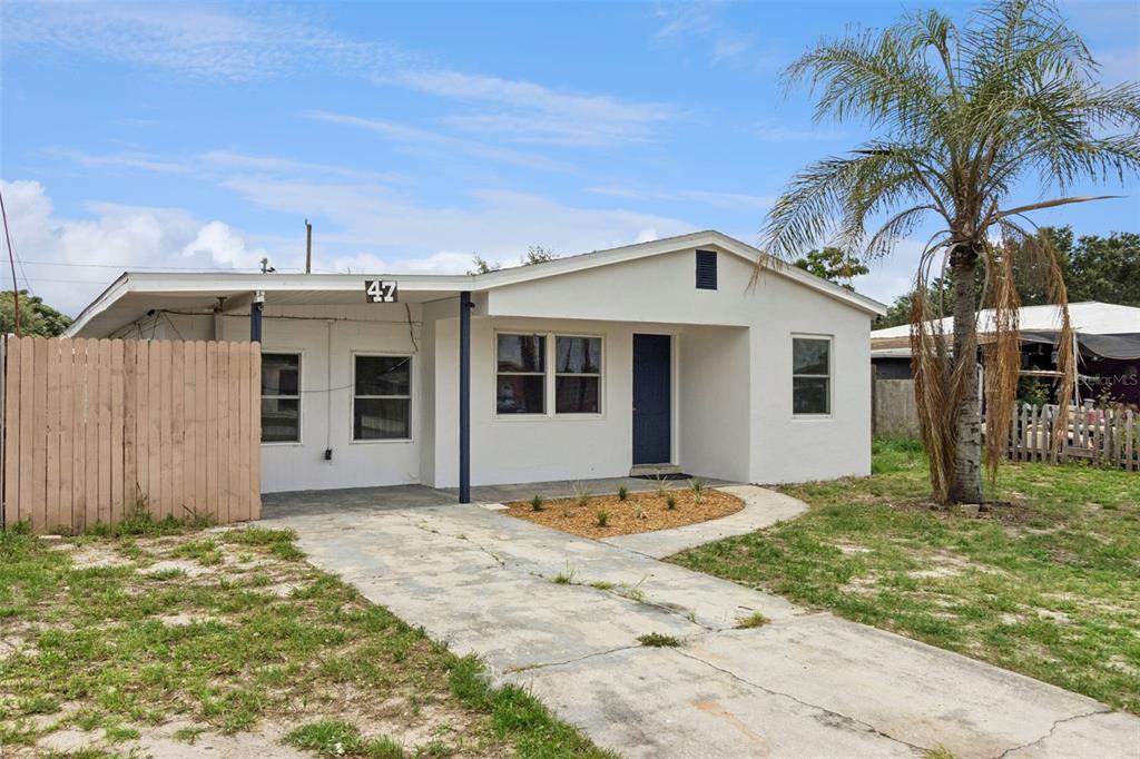 A white, single-story house with a concrete driveway, a wooden fence, and a palm tree — 47 PRINCETON AVENUE, FROSTPROOF, FL