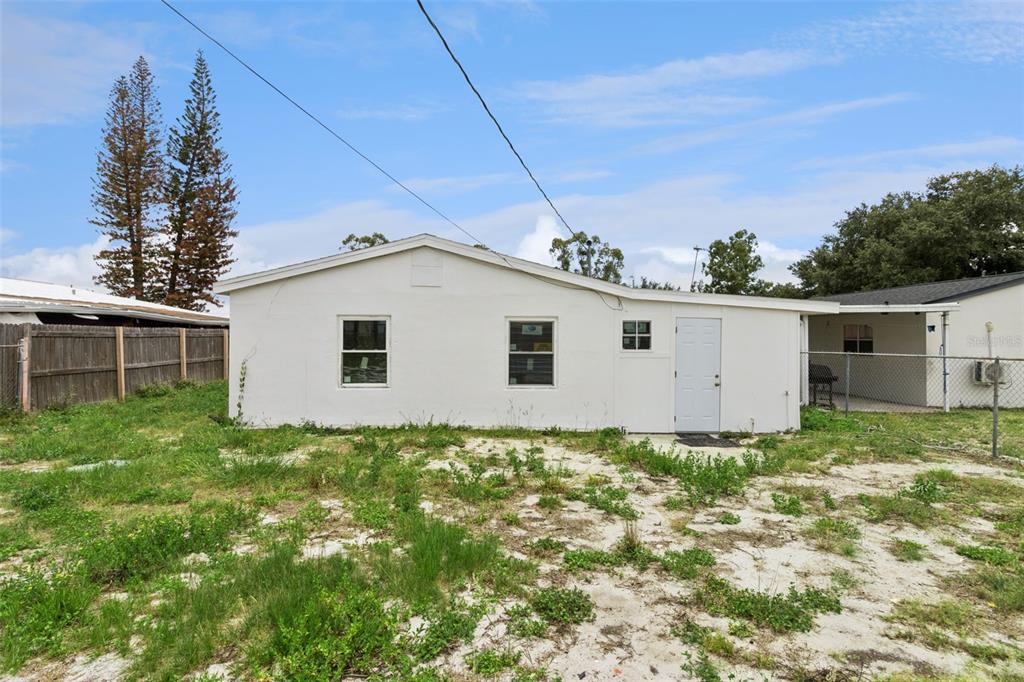 The exterior of a white, single-story house features a plain facade with a white door — 47 PRINCETON AVENUE, FROSTPROOF, FL