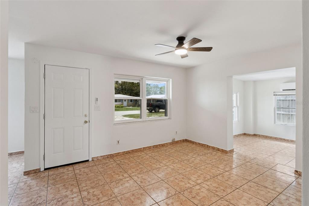 An empty room with tan tile flooring, a ceiling fan, and a white front door — 47 PRINCETON AVENUE, FROSTPROOF, FL