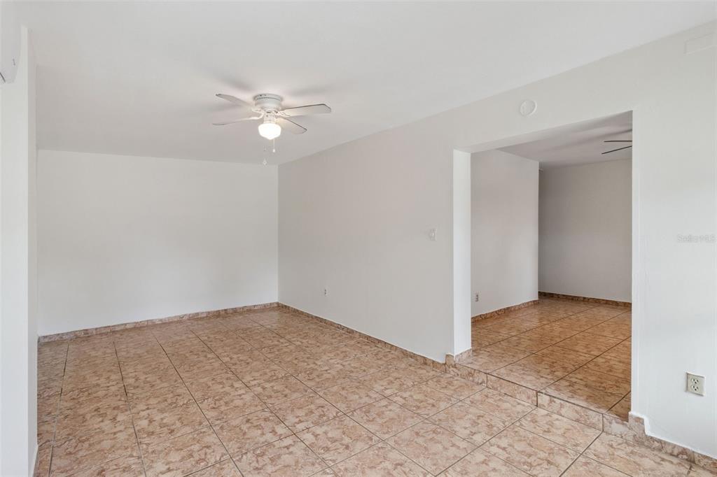 An empty room with light-colored walls and tan tiled flooring features a ceiling fan — 47 PRINCETON AVENUE, FROSTPROOF, FL