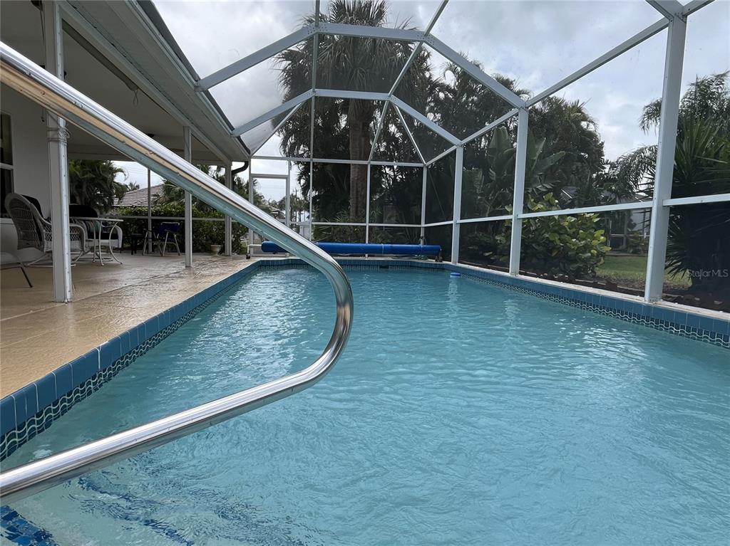 A rectangular swimming pool is enclosed by a white screen cage on a paved patio — 4041 KING TARPON DRIVE, PUNTA GORDA, FL