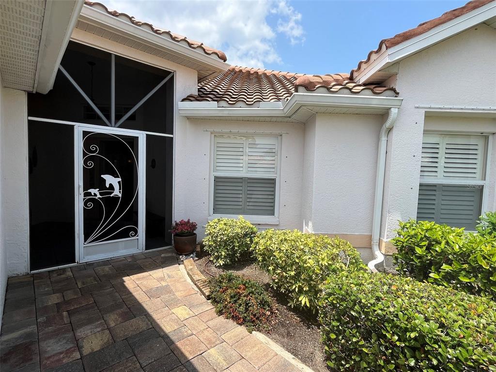 A paved walkway leads to a screened front entryway with a decorative dolphin-themed door — 4041 KING TARPON DRIVE, PUNTA GORDA, FL