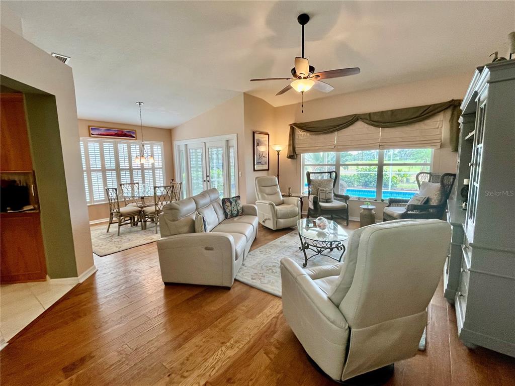 A living room with hardwood floors, a ceiling fan, and a view of a pool — 4041 KING TARPON DRIVE, PUNTA GORDA, FL