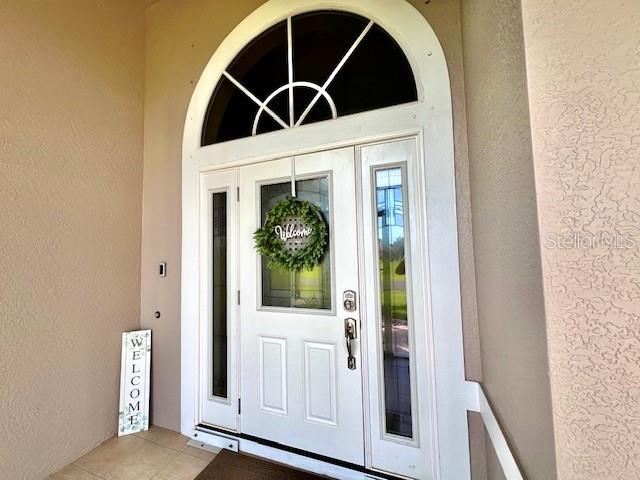 A white front door with a glass insert, side lights, and an arched transom window — 24378 BELIZE COURT, PUNTA GORDA, FL