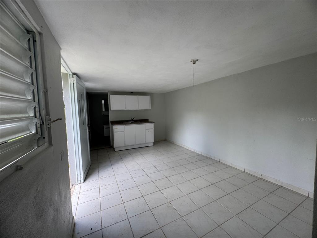 A small room with white tile floors, a kitchenette, and a door leading outside — 156 BO BAYAMONCITO, AGUAS BUENAS, PR