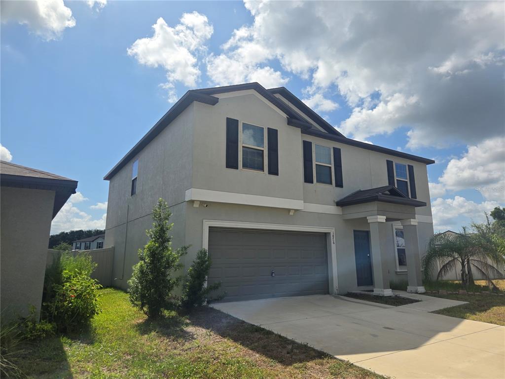 A two-story house with a gray stucco exterior, a two-car garage, and black shutters — 1876 COLDING DRIVE, RUSKIN, FL