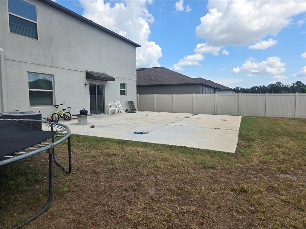 A concrete patio extends from the back of a two-story house with a vinyl fence — 1876 COLDING DRIVE, RUSKIN, FL