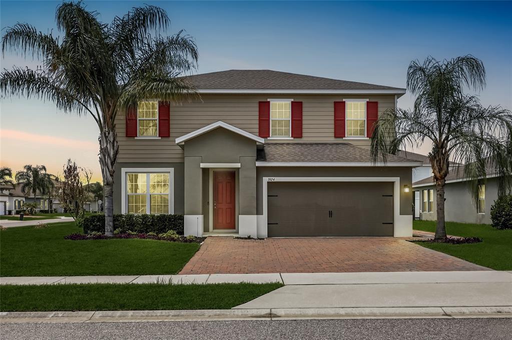 A two-story house with tan siding, red shutters, a brick driveway, and two palm trees — 3924 HANWORTH LOOP, SANFORD, FL