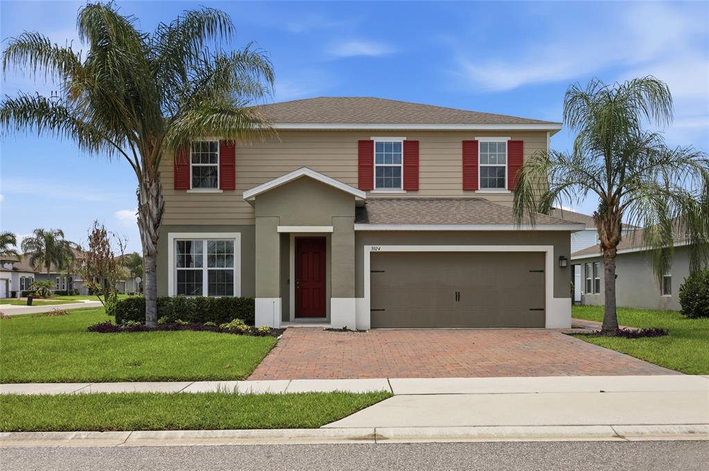 A two-story house with tan siding, red shutters, a brick driveway, and two palm trees — 3924 HANWORTH LOOP, SANFORD, FL