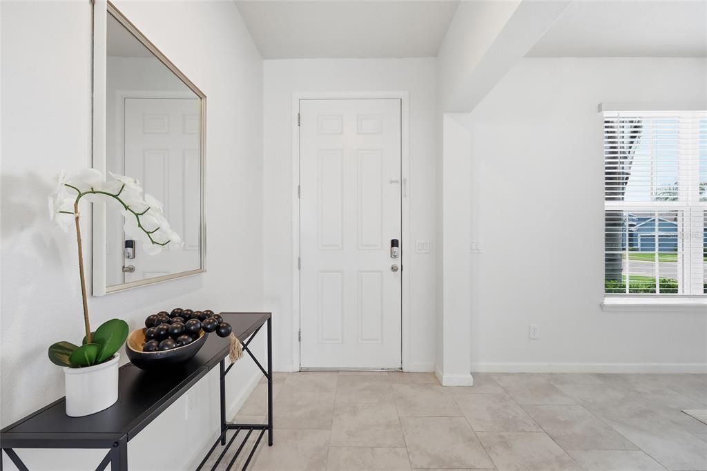 A bright entryway features white walls, tile flooring, a front door, and a console table — 3924 HANWORTH LOOP, SANFORD, FL