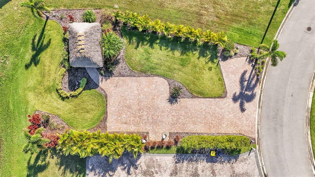 An aerial view shows a paved patio with a tiki hut and surrounding landscaped gardens — 2907 WOOD DUCK DRIVE, POLK CITY, FL