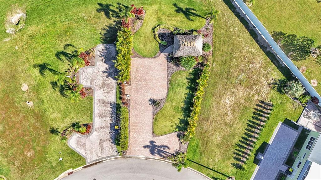 An aerial view shows a paved driveway leading to a tiki hut in a grassy yard — 2907 WOOD DUCK DRIVE, POLK CITY, FL
