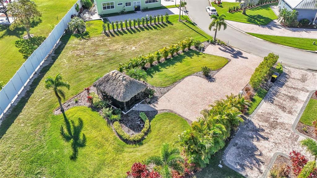 An aerial view shows a backyard with a thatched-roof gazebo, paved driveway, and landscaping — 2907 WOOD DUCK DRIVE, POLK CITY, FL