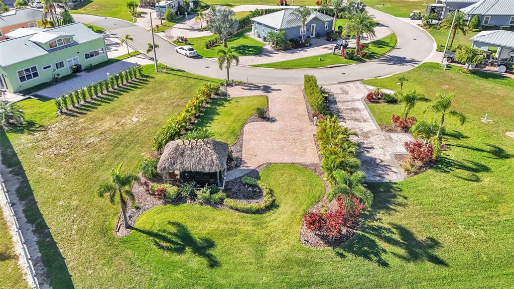 An aerial view shows a landscaped residential lot featuring a tiki hut and paved driveway — 2907 WOOD DUCK DRIVE, POLK CITY, FL