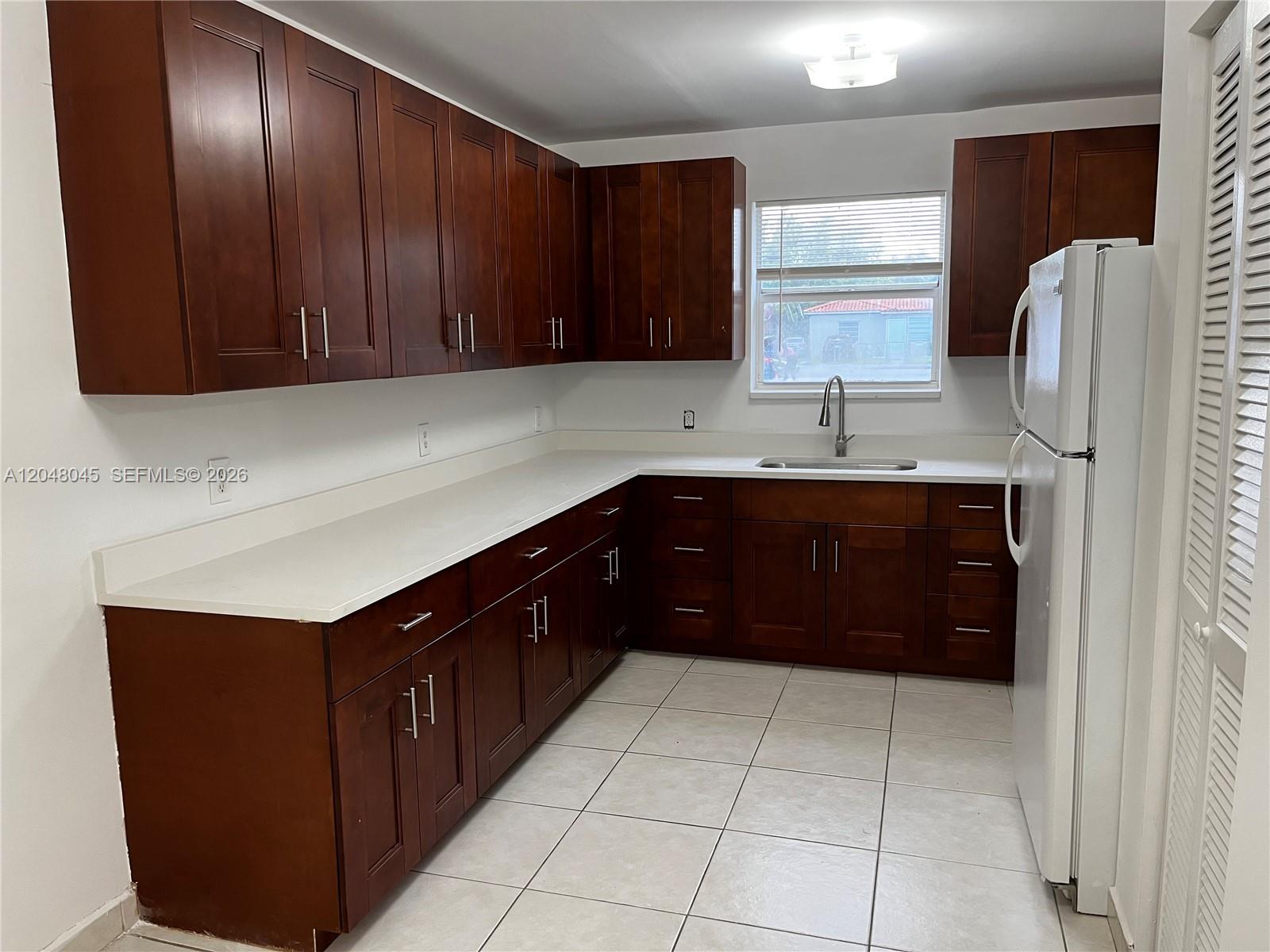 A kitchen features dark wood cabinets, white countertops, a stainless steel sink, and tile flooring — 181 NW 47th Ave # 9, Miami FL 33126, MIAMI, FL