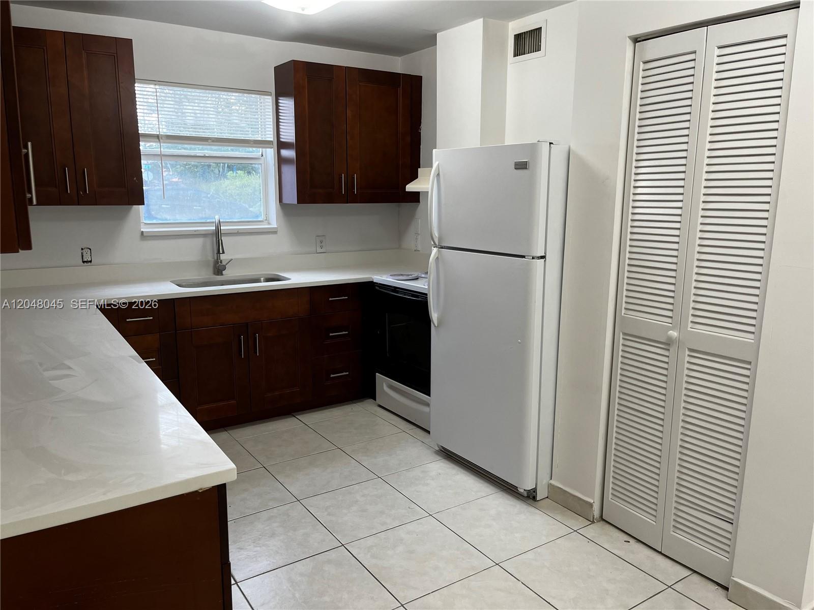 A kitchen features dark wood cabinets, white countertops, white appliances, and light-colored floor tiles — 181 NW 47th Ave # 9, Miami FL 33126, MIAMI, FL