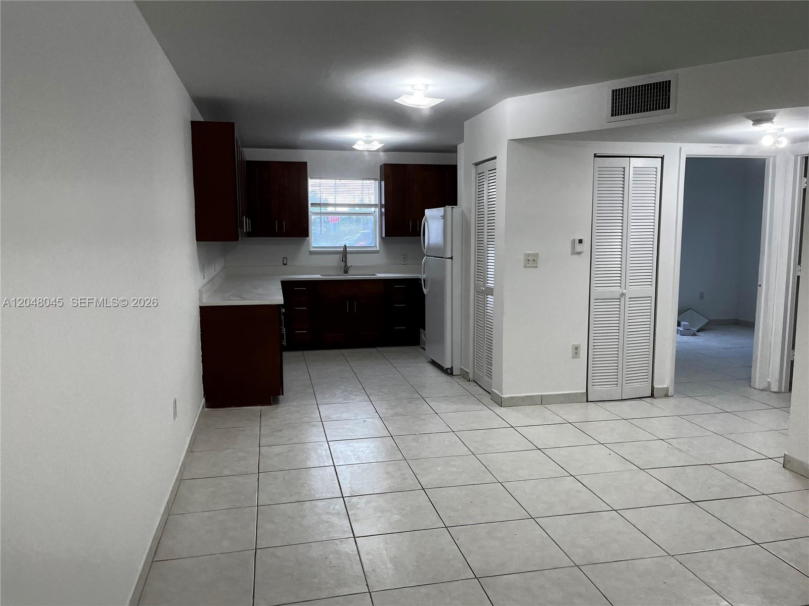 A kitchen features dark wood cabinets, white countertops, tile flooring, and a white refrigerator — 181 NW 47th Ave # 9, Miami FL 33126, MIAMI, FL