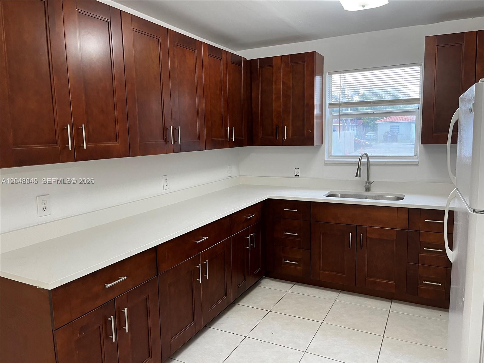 A kitchen features dark wood cabinets, white countertops, and a stainless steel sink — 181 NW 47th Ave # 9, Miami FL 33126, MIAMI, FL