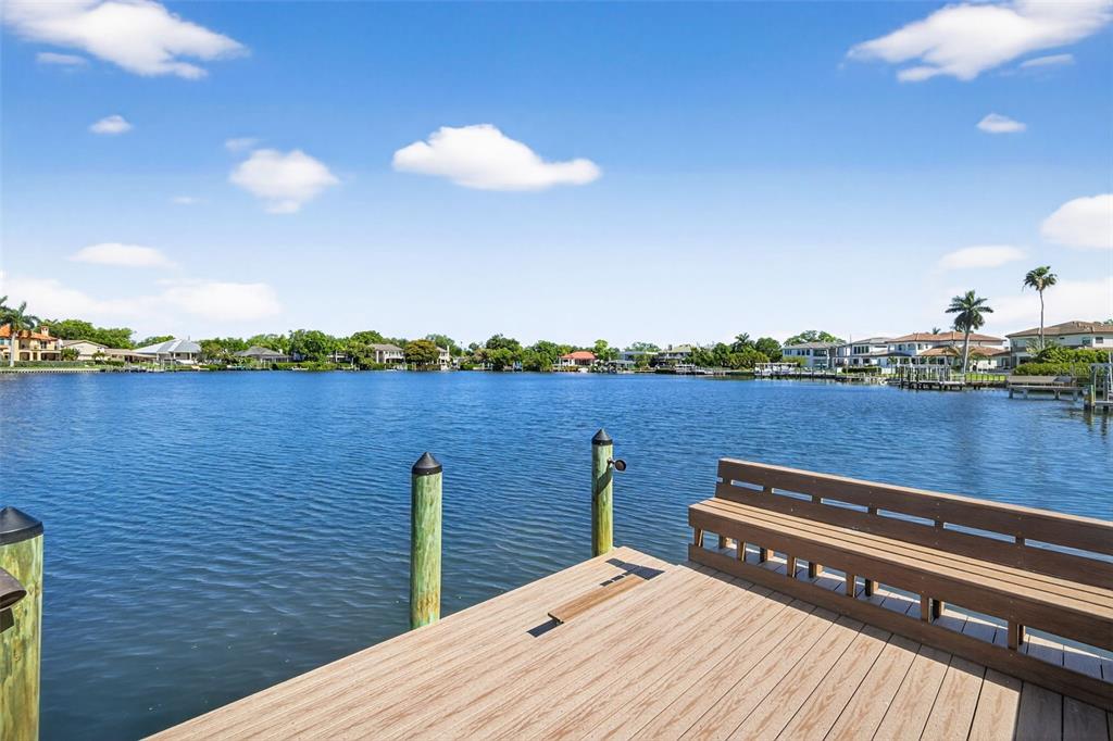 A wooden dock with a bench overlooks a calm lake surrounded by residential houses — 460 COFFEE POT RIVIERA NE, ST PETERSBURG, FL