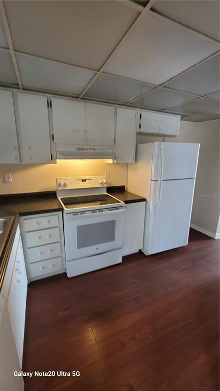 A kitchen features white cabinets, a white stove, a white refrigerator, and dark wood flooring — 122 N KINGS AVENUE UNIT 202, BRANDON, FL