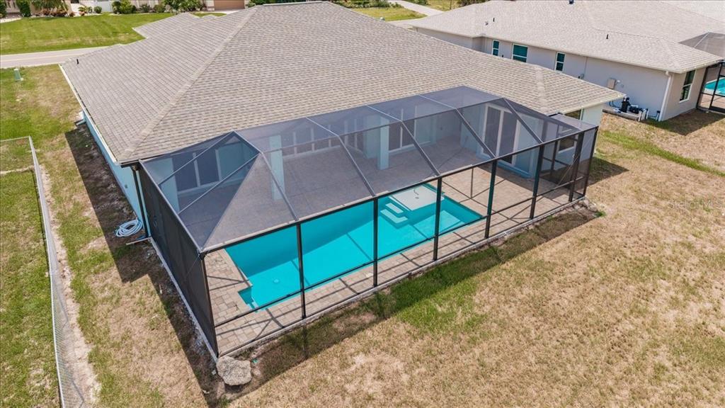 An aerial view of a house with a screened-in pool and patio in the backyard — 779 BOUNDARY BOULEVARD, ROTONDA WEST, FL