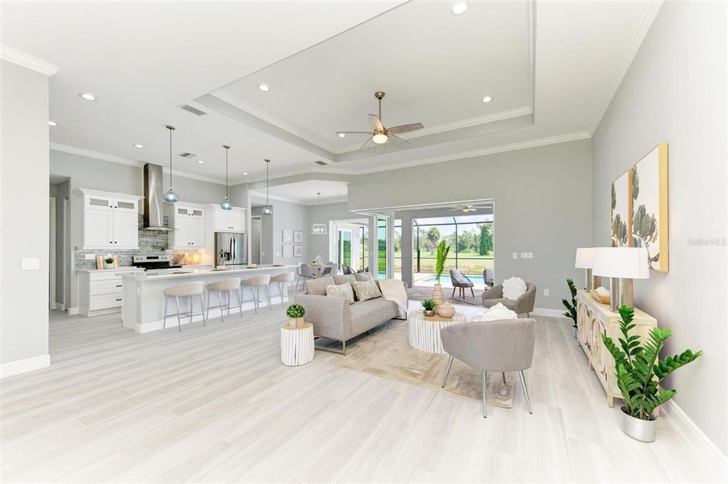 A bright, open-concept living room and kitchen featuring light wood floors and a pool view — 779 BOUNDARY BOULEVARD, ROTONDA WEST, FL