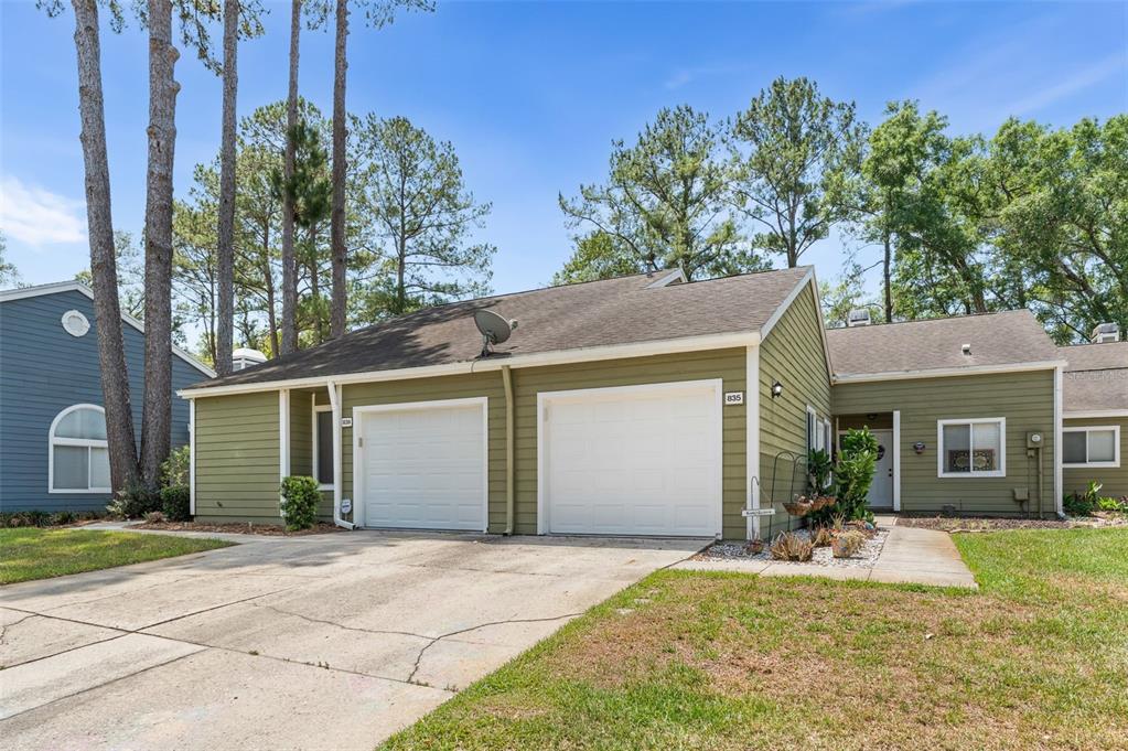 A single-story house with olive green siding, two white garage doors, and a concrete driveway — 839 NW 125TH DRIVE, NEWBERRY, FL