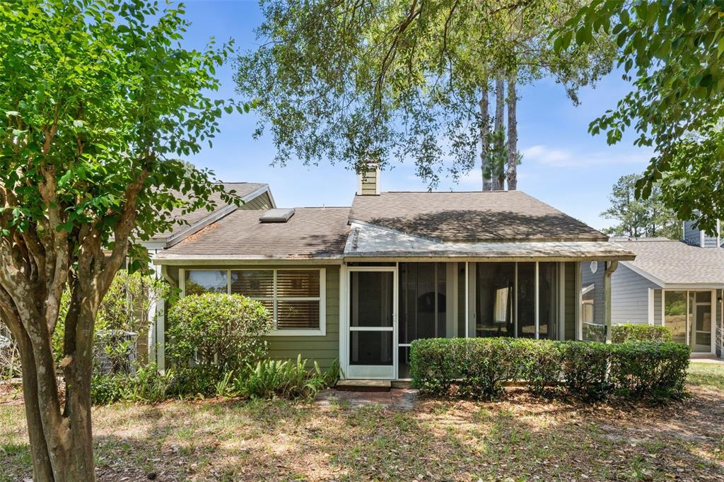 The exterior of a single-story home features green siding, a screened porch, and a chimney — 839 NW 125TH DRIVE, NEWBERRY, FL