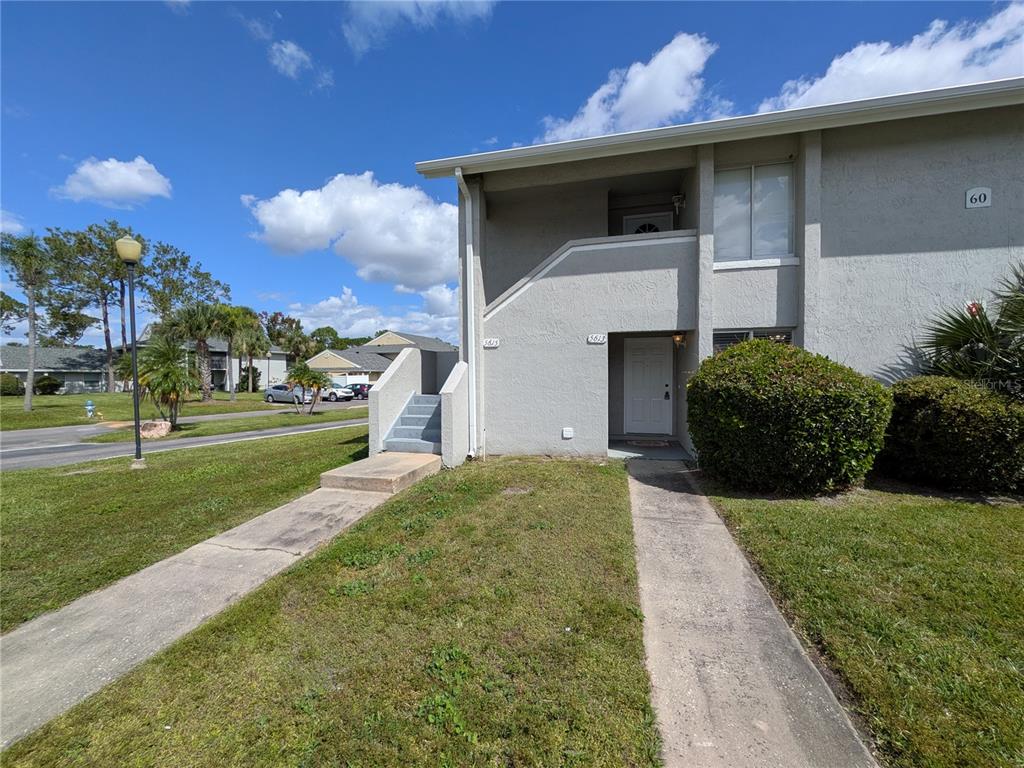 A two-story gray stucco apartment building with exterior stairs and two separate entry doors — 5613 BLUE SHADOWS COURT UNIT 60-2, ORLANDO, FL