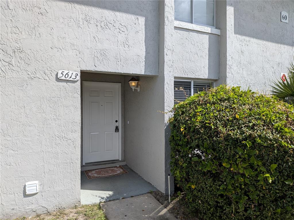 A white front door with a house number is set into a gray stucco exterior — 5613 BLUE SHADOWS COURT UNIT 60-2, ORLANDO, FL