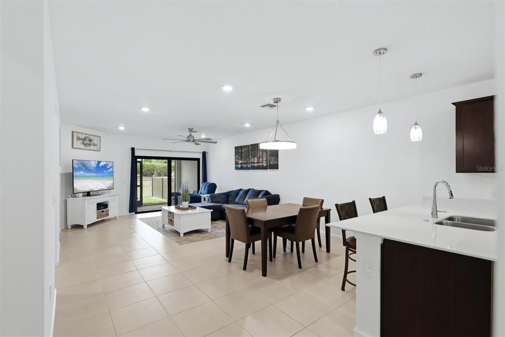 An open-concept living and dining area features tile flooring, a kitchen island, and sliding doors — 6499 SILVERSTAR DRIVE, SARASOTA, FL