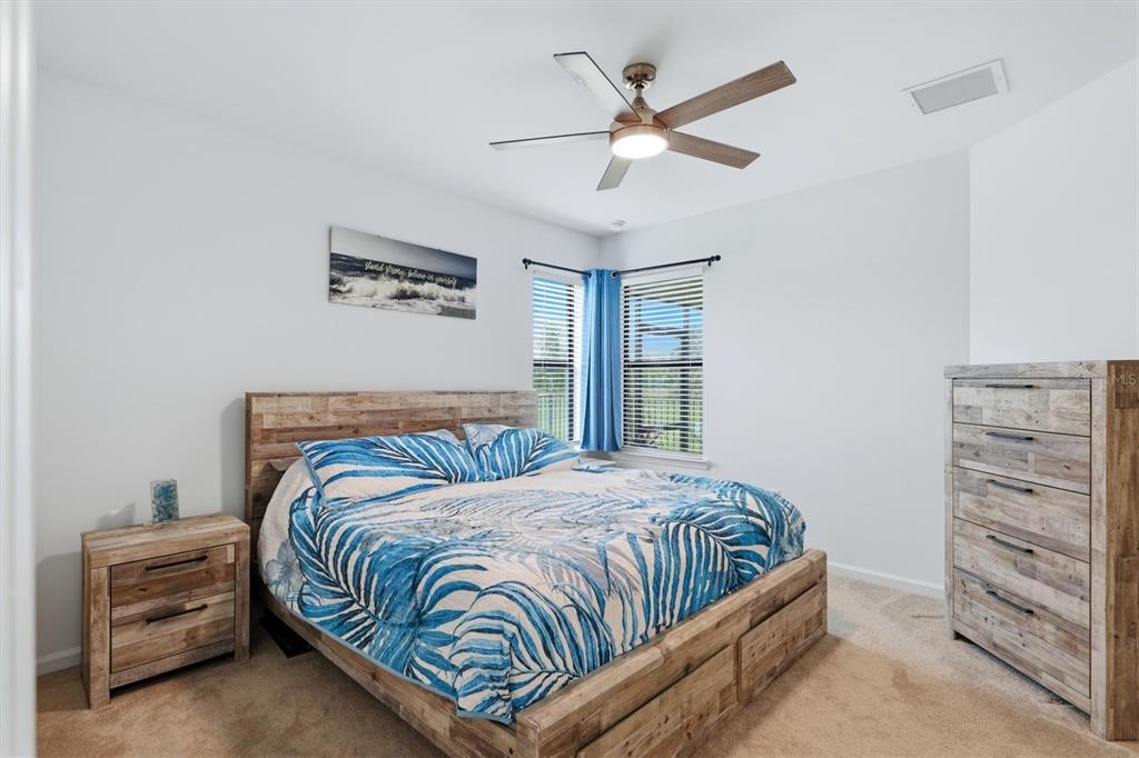 A bedroom features a wooden bed frame, matching dresser, nightstand, and a blue patterned comforter — 6499 SILVERSTAR DRIVE, SARASOTA, FL