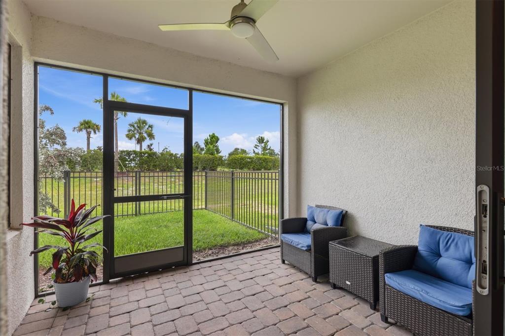 A covered patio with a brick floor, wicker chairs, a ceiling fan, and a screened door — 6499 SILVERSTAR DRIVE, SARASOTA, FL