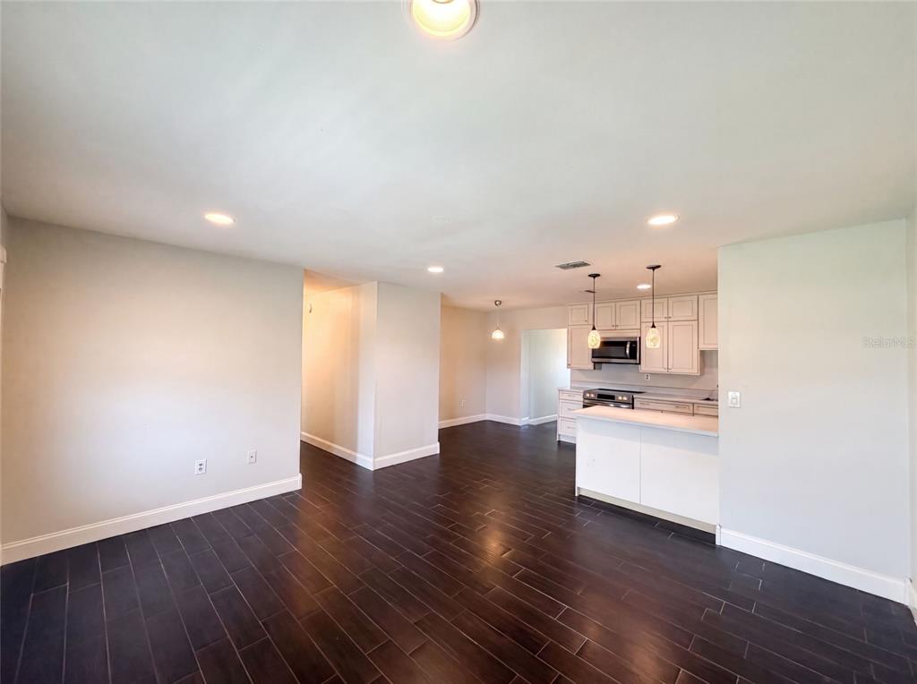 An open-concept living area features dark wood-look tile flooring and a kitchen with white cabinetry — 4147 WILLOW SOUTH DRIVE, MULBERRY, FL