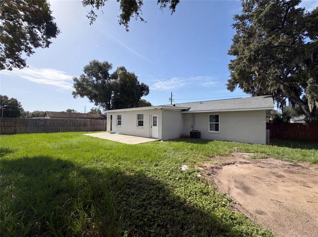 The exterior of a single-story house with a concrete patio and a large grassy backyard — 4147 WILLOW SOUTH DRIVE, MULBERRY, FL