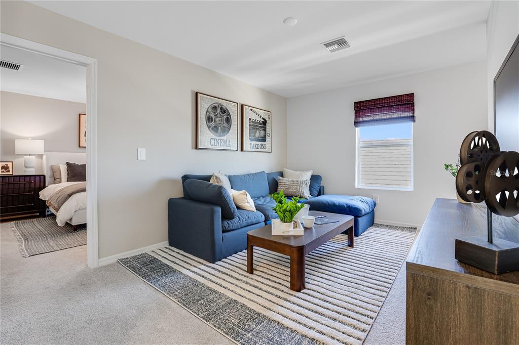 A living room features a blue sectional sofa, a coffee table, and cinema-themed wall art — 18055 MELLON STREET, PARRISH, FL