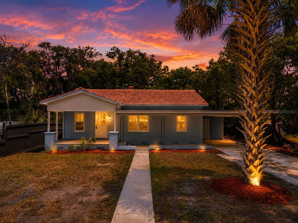 A single-story house with a tiled roof and a front porch at sunset — 1504 W LINE STREET, LEESBURG, FL