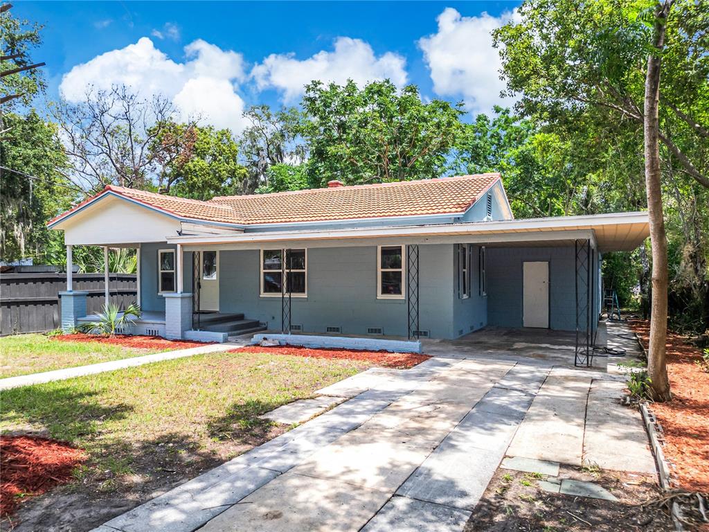 A single-story blue house with a tiled roof, front porch, and attached carport — 1504 W LINE STREET, LEESBURG, FL