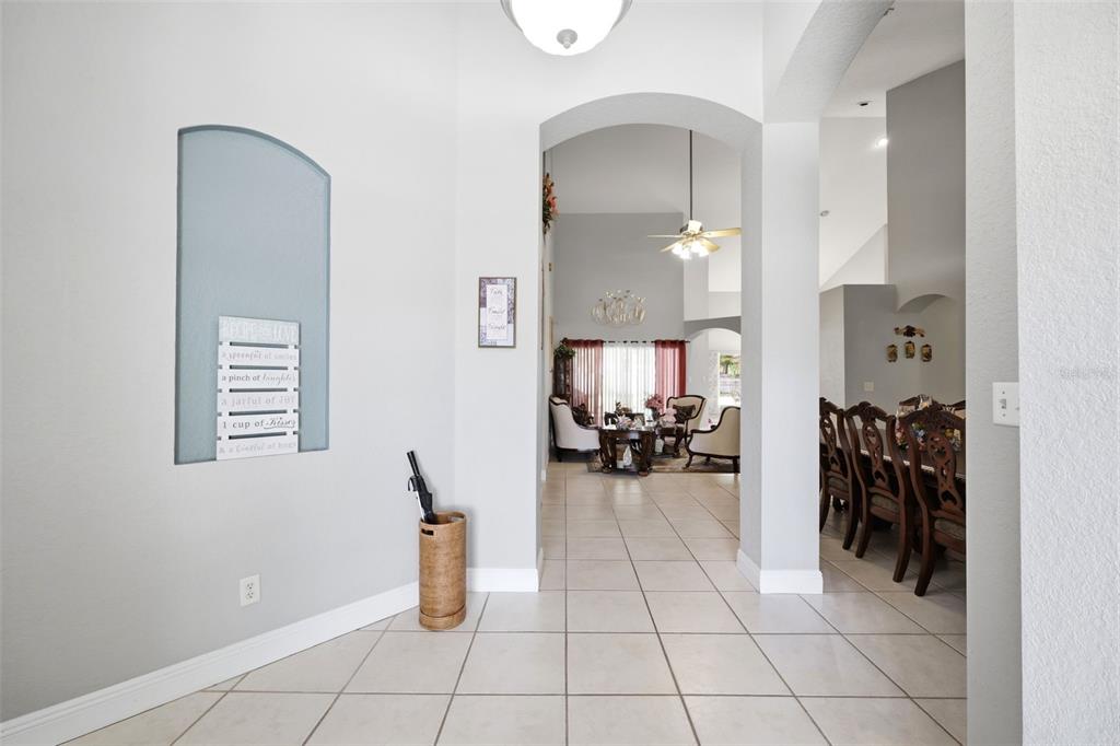 A tiled entryway leads through an arched doorway into a living room and dining area — 2112 HERITAGE CREST DRIVE, VALRICO, FL
