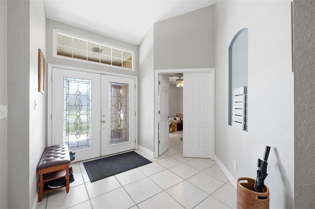 An entryway features a double front door, tiled floors, a bench, and an arched wall niche — 2112 HERITAGE CREST DRIVE, VALRICO, FL