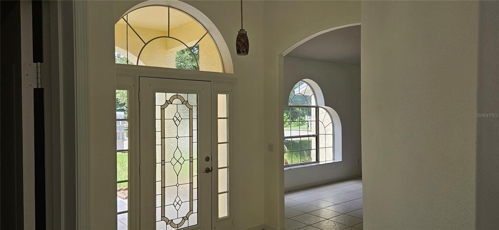 A front entryway featuring a white door with decorative glass, sidelights, and an arched transom window — 1510 GAYNOR COURT, DELTONA, FL