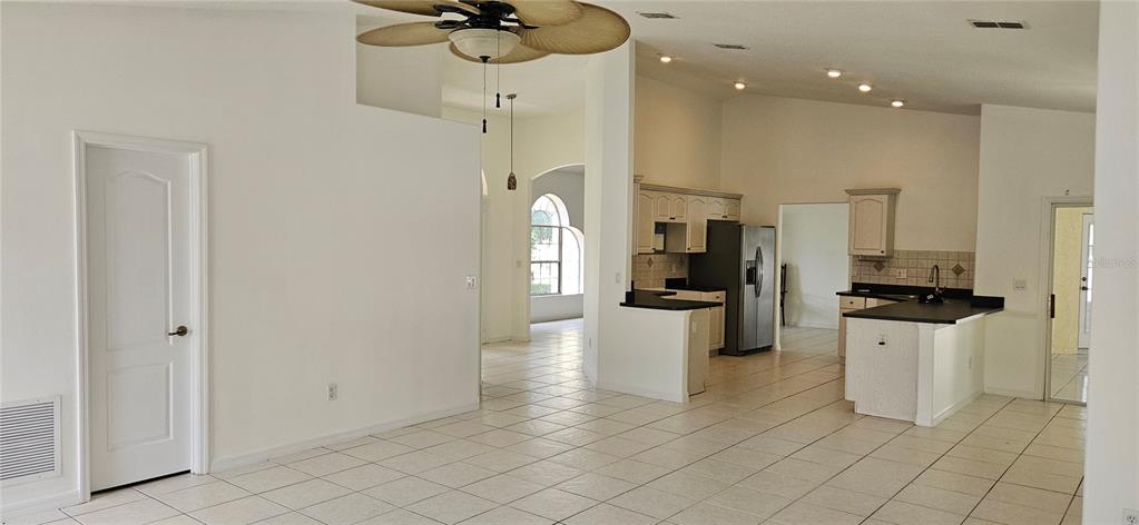 A bright entryway features a glass-paneled front door, arched windows, and light-colored tile flooring — 1510 GAYNOR COURT, DELTONA, FL