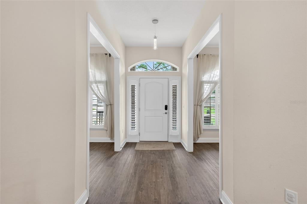 A bright entryway features wood-look flooring, a white front door, and side windows with curtains — 14 FARNELL LANE, PALM COAST, FL