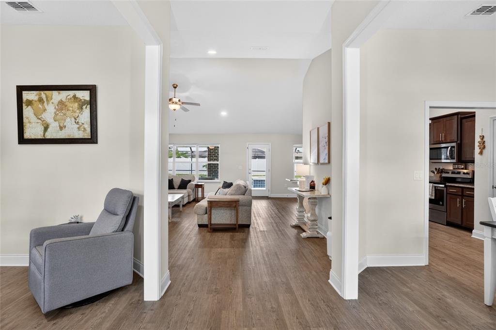 A view through a doorway into a living room with wood-look flooring and a kitchen — 14 FARNELL LANE, PALM COAST, FL