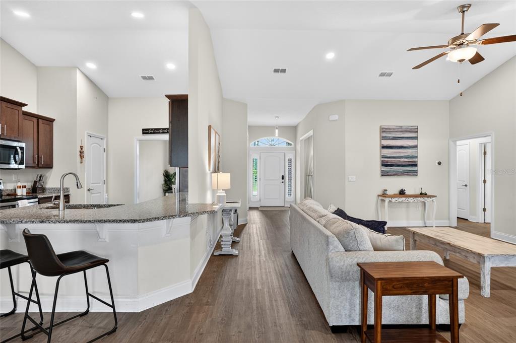 A kitchen with a breakfast bar overlooks a living room featuring a sofa and ceiling fan — 14 FARNELL LANE, PALM COAST, FL