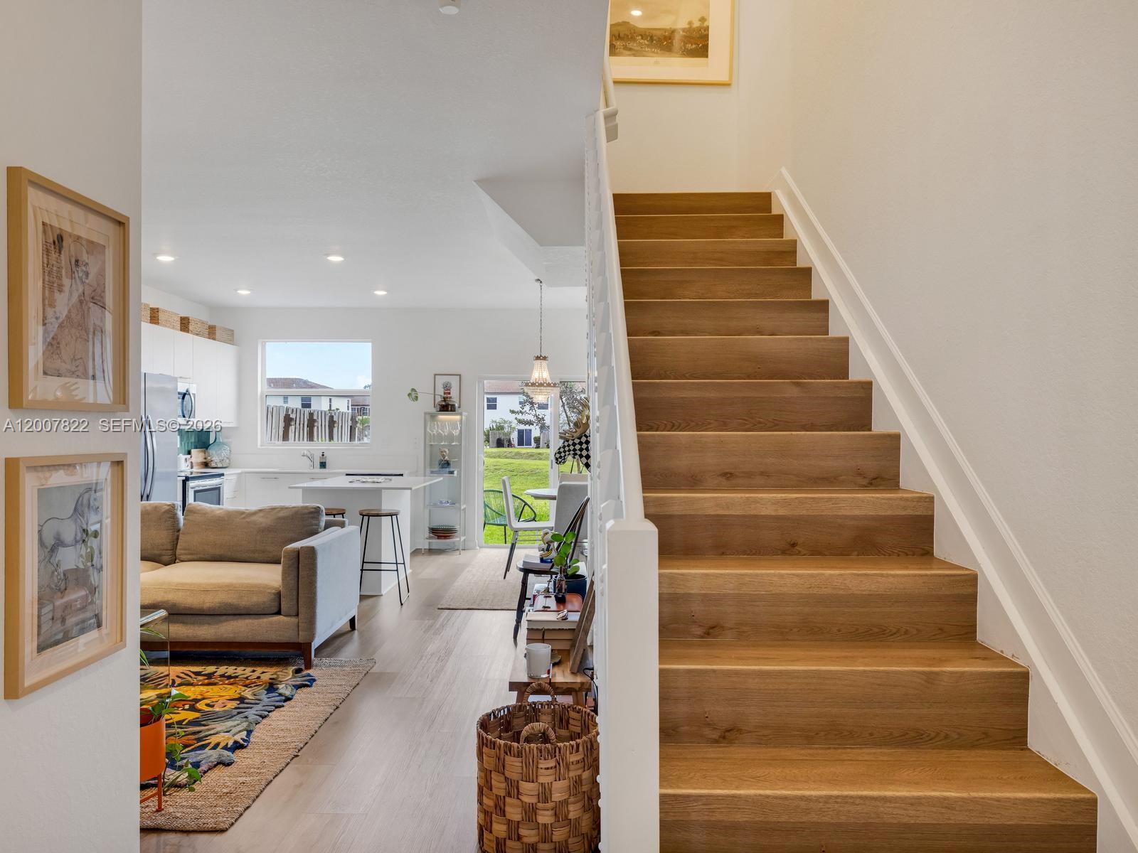 A wooden staircase leads up beside an open-concept living area with a kitchen — 2349 NW 122nd Ter, Miami FL 33167, MIAMI, FL