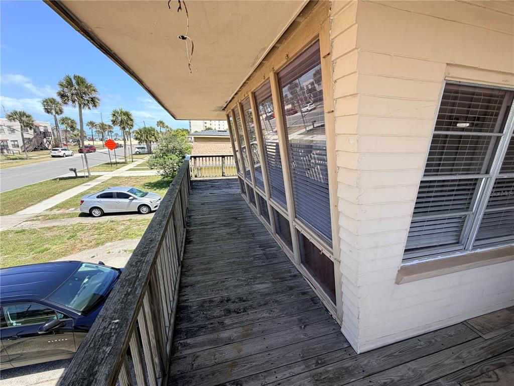 A wooden balcony overlooks a street with parked cars and palm trees — 538 REVILO BOULEVARD, DAYTONA BEACH, FL