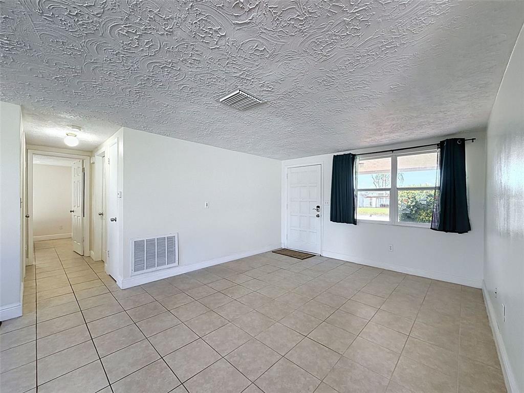 A living room with beige tile floors, white walls, and a textured ceiling — 3345 CHAUNCY ROAD, HOLIDAY, FL